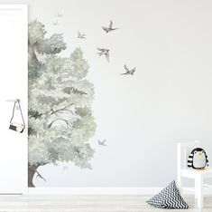 a room with a tree and birds painted on the wall next to a white door