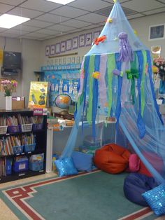 a room filled with lots of toys and books on the floor in front of a tent