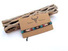 the beaded bracelet is on display next to some driftwood sticks and a tag