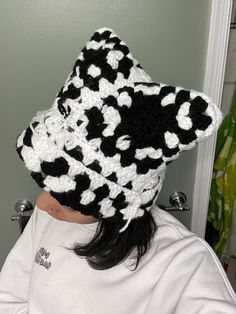 a woman wearing a black and white crocheted hat with flowers on the brim