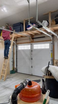 a man standing on top of a ladder in a garage