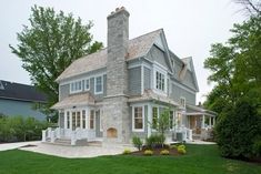 a large gray house sitting on top of a lush green field