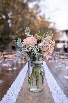 a vase filled with flowers sitting on top of a table next to a white runner