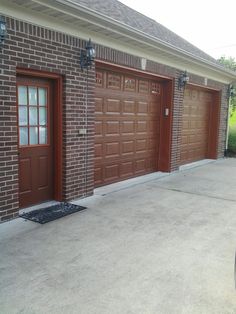 two brown garage doors in front of a brick building