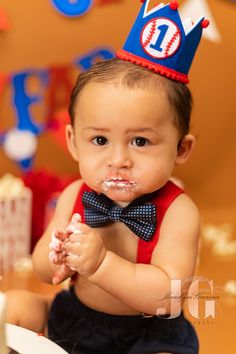 a baby wearing a birthday hat and eating cake