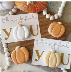 three decorated cookies sitting on top of a cutting board next to some thank you cards