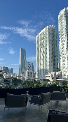 chairs and couches on the roof of a building with skyscrapers in the background