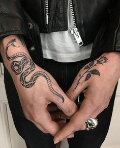 a person with tattoos on their hands and two fingers in the shape of a snake