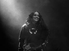 a black and white photo of a woman with long hair standing in front of a spotlight