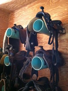 there are many horse saddles and hats hanging on the wall with cups in them