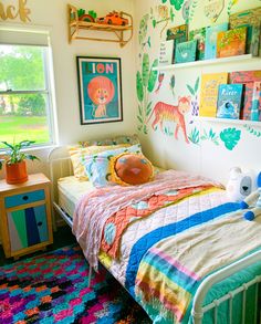 a bed room with a neatly made bed next to a window and colorful rugs on the floor