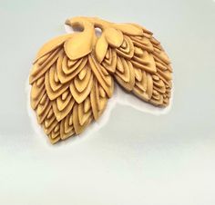 an intricately carved brooch sits on a white surface in the shape of a leaf