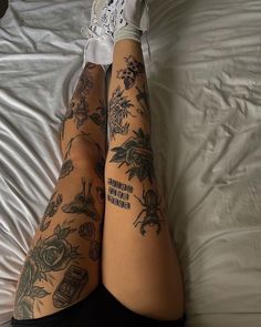 a woman with tattoos on her legs laying in bed