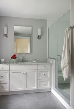 a white bathroom with two sinks and a large mirror above the sink is next to a walk in shower