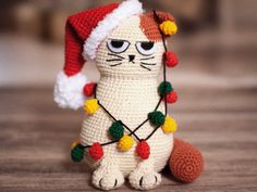 a crocheted cat with a christmas hat and lights around it's neck