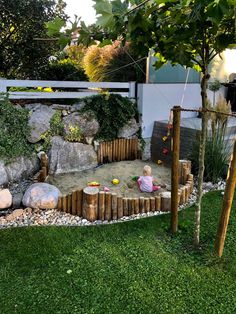 a small child is playing in the sandbox with rocks and wood logs around it