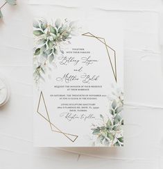 a wedding card with flowers and greenery on it