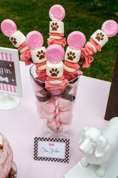 pink and white desserts in a glass vase on a table with dog themed decorations