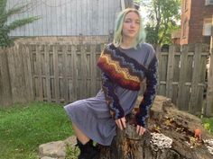 a woman sitting on top of a tree stump