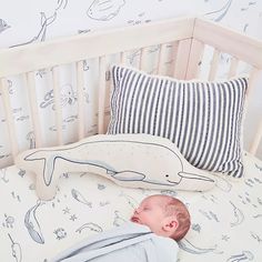 a baby is sleeping in his crib next to a pillow and stuffed toy whale