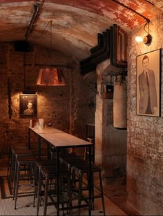 the interior of a bar with wooden tables and stools in an old brick building