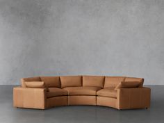 a tan leather sectional sofa in front of a gray wall with no one sitting on it