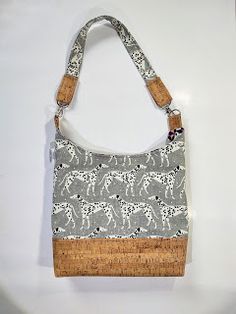 an animal print purse is hanging on a white wall and has a cork handle to hold it