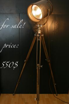 a tripod light sitting on top of a wooden floor next to a black wall