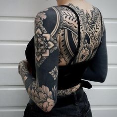 the back of a woman's body with tattoos on her arm and shoulder,