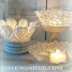 two glass bowls with lace doily on them and a lit candle in the middle