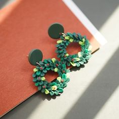 a pair of green and yellow earrings sitting on top of a piece of red paper