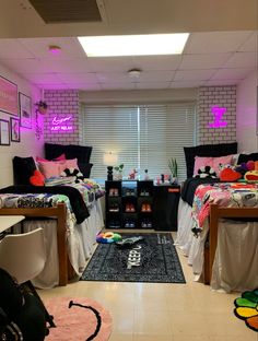 two twin beds in a dorm room with pink lights on the windowsill and rugs