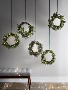 three wreaths hanging from the ceiling with lights on them and a bench in front