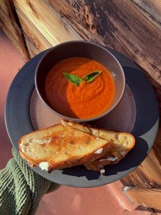 a bowl of tomato soup and grilled cheese sandwich on a plate