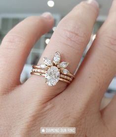 a woman's hand with a diamond ring on top of her finger and an engagement ring in the middle