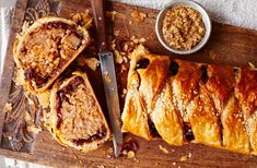 a wooden cutting board topped with pastries next to a knife