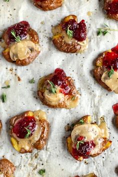 small appetizers with cranberry sauce and herbs are on a sheet of wax paper