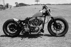 a black and white photo of a motorcycle parked on the grass in front of a building