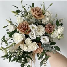 a bouquet of white and brown flowers in someone's hand on a white background