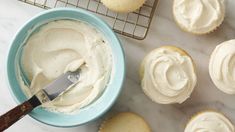 cupcakes with white frosting and a knife on a cooling rack next to them