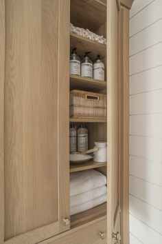 an open cabinet with white towels and other items in the cupboards next to it