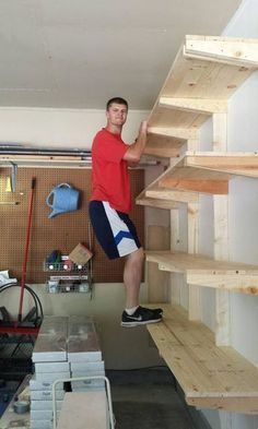 a man standing on top of a wooden shelf next to a pile of boxes and shelves