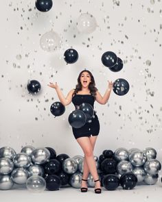 a woman in a black dress is surrounded by balloons and confetti as she poses for the camera