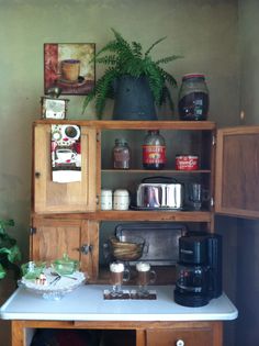 an old fashioned coffee maker is on top of a kitchen counter next to a potted plant