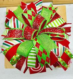 a red, green and white christmas wreath on top of a cutting board with scissors