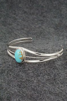 This turquoise and sterling silver bracelet was made by Navajo silversmith Alice Rose Saunders.Size: 5 1/8" (will fit up to a 6 1/2" wrist)Gap: 1 3/8"Width: 5/8"Cuff Width: 1/4"Free shipping on all orders! We ship with USPS and always include tracking. All orders ship within a day of payment.Returns are accepted up to 30 days after you receive your order. Just send us a message. Our shop offers cash back or store credit. The item must be returned in new condition. Classic Turquoise Sterling Silver Bracelets, Adjustable Turquoise Bracelet With Polished Finish, Adjustable Turquoise Bracelets With Polished Finish, Adjustable Southwestern Sterling Silver Bracelet With Turquoise, Adjustable Turquoise Sterling Silver Bracelet In Southwestern Style, Adjustable Southwestern Turquoise Sterling Silver Bracelet, Oval Southwestern Sterling Silver Cuff Bracelet, Adjustable Oval Turquoise Sterling Silver Bracelet, Southwestern Oval Sterling Silver Cuff Bracelet