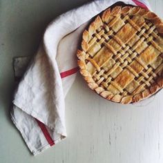 a pie sitting on top of a white table next to a napkin and spoons