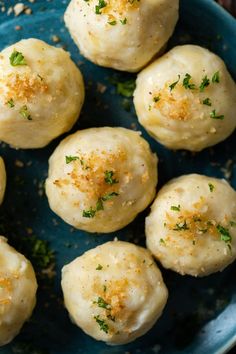 a blue plate topped with dumplings covered in cheese and parmesan sprinkles