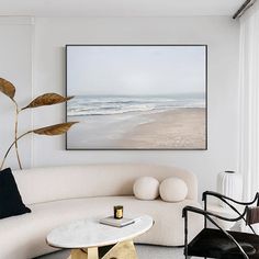 a living room filled with furniture and a painting hanging on the wall over a white couch