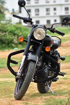 a black motorcycle parked on top of a lush green field next to a white building